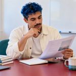 Common Myths About Reiki: 12 Misunderstandings, Corrected A man reviews a teaching handout in a bright classroom.