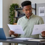 Reiki’s “Healing Power”: Why Case Studies Cannot Show It, in Brief A man compares printed study summaries beside a laptop in a modern study corner.