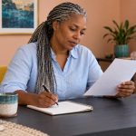 Reiki Psychic Surgery: Claims, Risks and Safer Choices A woman reads an information leaflet and writes questions at a desk.