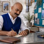 Affirmations: Realistic Reminders, Values Reflection and Practical Plans A man writes a small reminder card beside a pinboard.