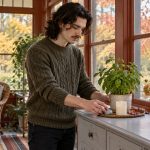 Autumn “Protection” Rituals: What They Are, Honestly, in Brief A man arranges a small stone and battery candle beside a basil plant on an autumn porch.
