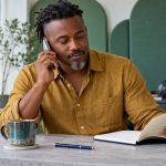 Getting the Most From a Psychic Reading: How to Prepare, What to Ask, and the Red Flags to Hang Up On A man checks a question notebook while speaking on a phone.