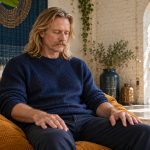 Using Reiki to Clear Your Mind: What It Really Does, in Brief A man sits quietly with hands resting on his thighs in a bright loft.