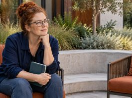 Empaths in Romantic Relationships: 5 Real Challenges and What Actually Helps A woman pauses with a closed notebook in a quiet courtyard.
