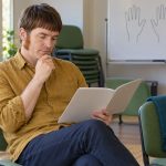 Reiki for Beginners: First Steps, Choosing a Level 1 Course and Honest Expectations A man reads a course booklet in a quiet learning room.