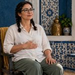 How to Do Reiki: A Beginner’s Guide to Self-Practice, Training and Limits A seated woman tries a comfortable hand position during a quiet self-practice.
