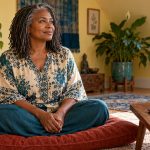 Understanding Long-Distance Reiki: The Practice, the Tradition and Its Limits A woman sits alone in a quiet practice room beside a closed laptop and appointment card.
