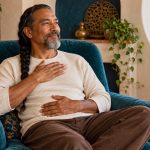 Self-Reiki Practice: A Comfortable Routine and Clear Limits A seated man rests his hands lightly on his chest and abdomen during a quiet self-practice.