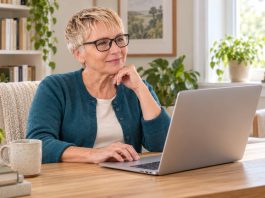 Reiki Safety Guide: Risks, Boundaries, and Medical Care A woman researching Reiki safety online on a silver laptop in a bright home study.